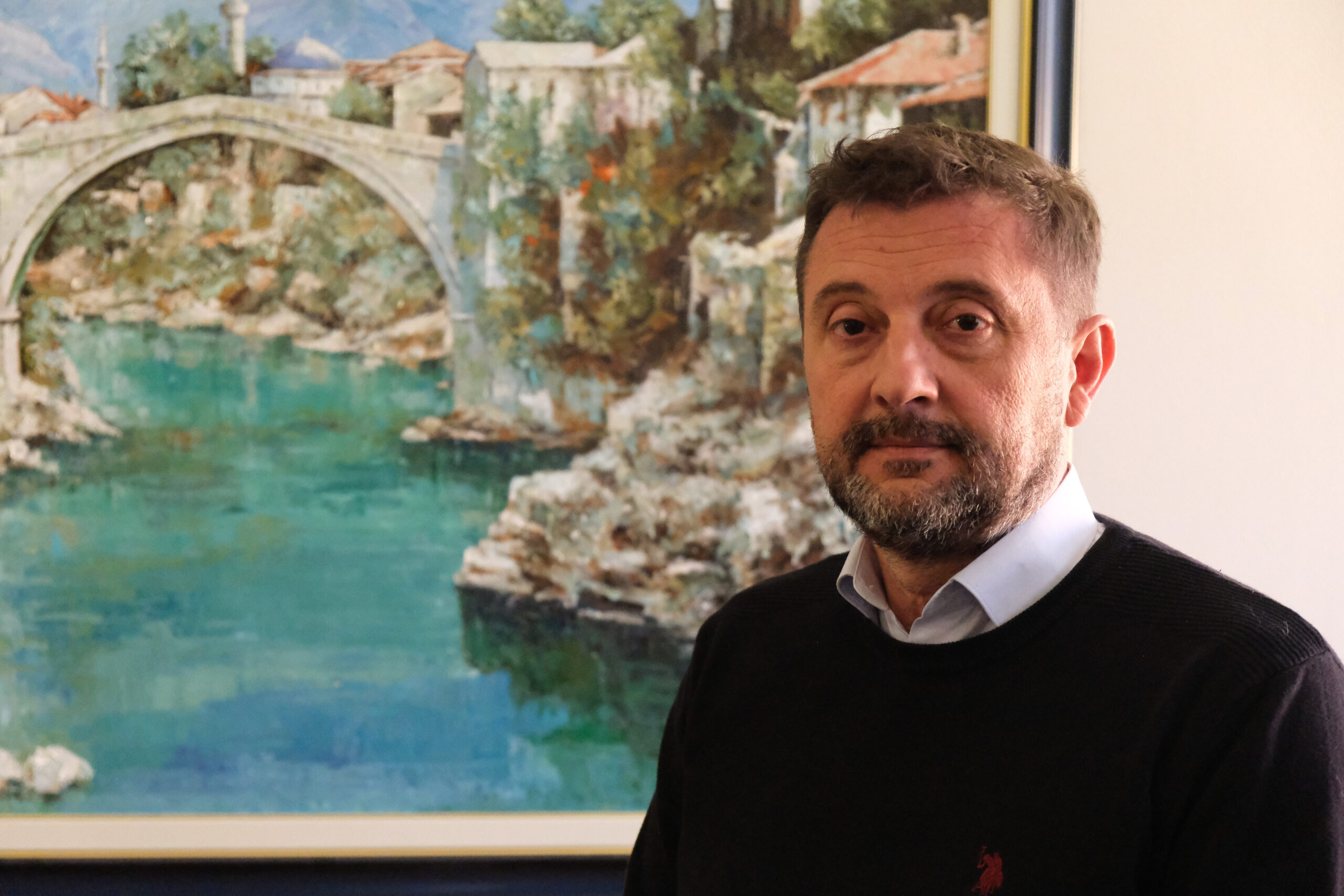 Mario Kordić, le maire de Mostar, devant un cadre représentant le pont de la ville.