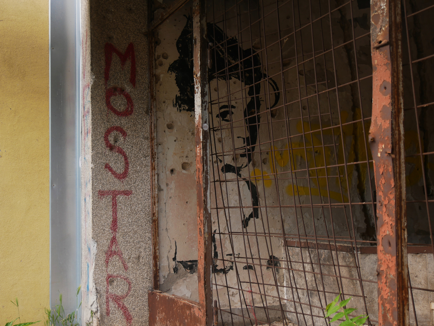Un tag derrière la grille d’un bâtiment abîmé par la guerre à Mostar. Un tag derrière la grille d’un bâtiment abîmé par la guerre à Mostar.